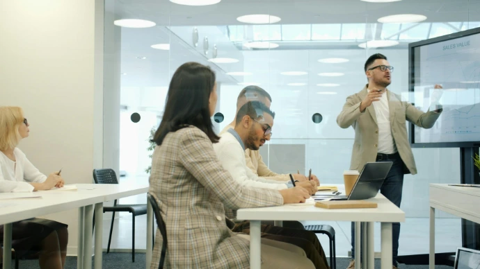 Man presenting to colleagues in a modern office meeting room.